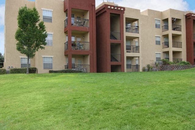 an apartment building with a green lawn in front of it